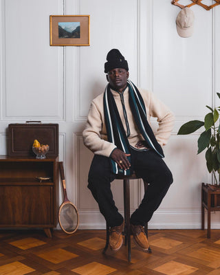 Man sitting on a wooden stool wearing a Val Mont Lac outfit