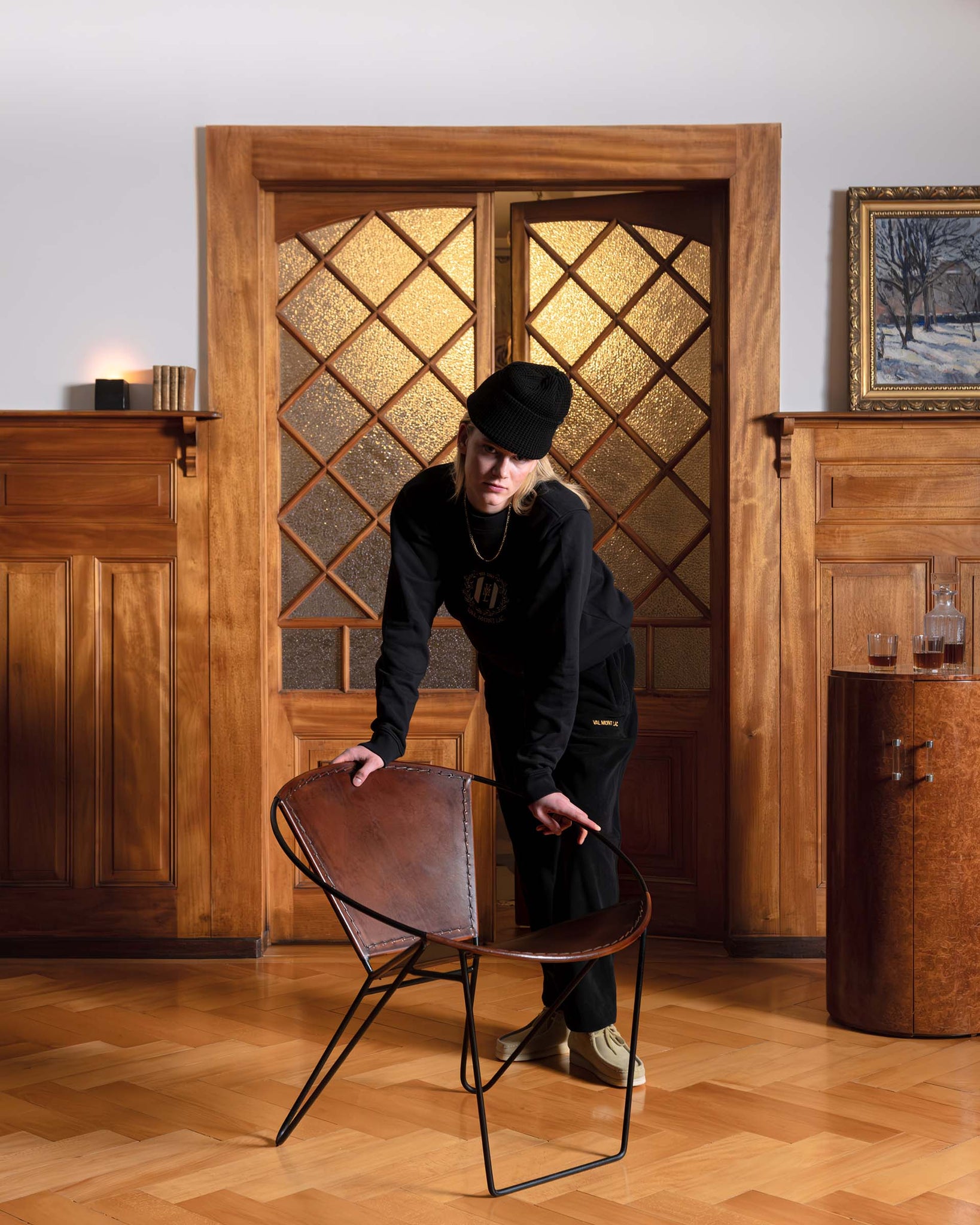 Woman wearing a Val Mont Lac clothing outfit leaning on a vintage designer chair in a Swiss chalet