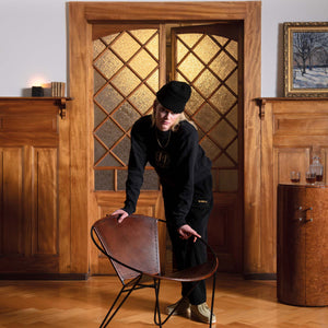 Frau in einem Val Mont Lac Kleidungsstück lehnt auf einem Vintage-Designerstuhl in einem Schweizer Chalet